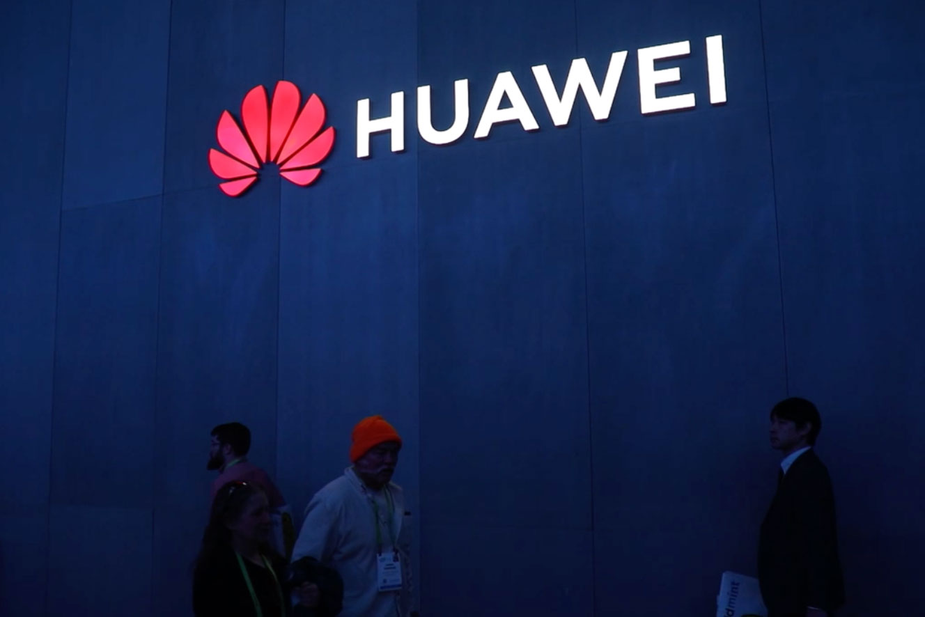 Personas caminando bajo el logo de Huawei