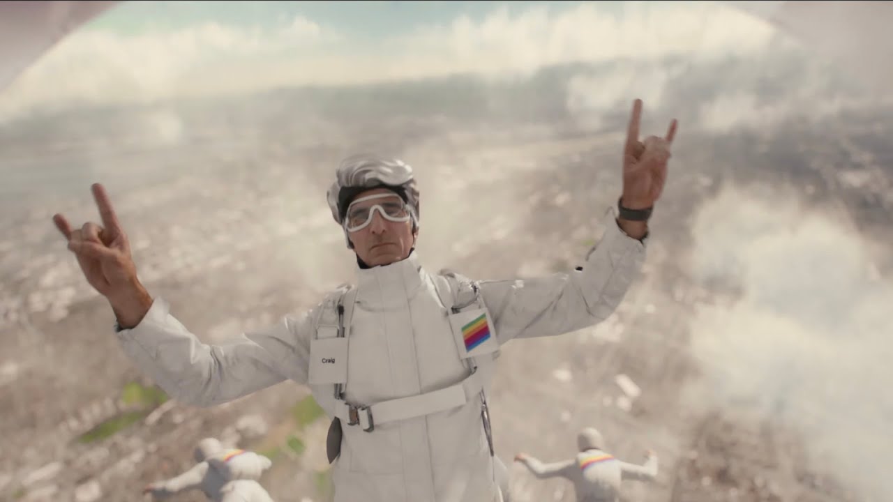Craig Federighi en el vídeo de apertura de la WWDC 2024, tirándose de un Avión con el símbolo de los cuernos en las manos