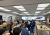 La gente haciendo cola en una Apple Store, con carteles del iPhone 17 de fondo