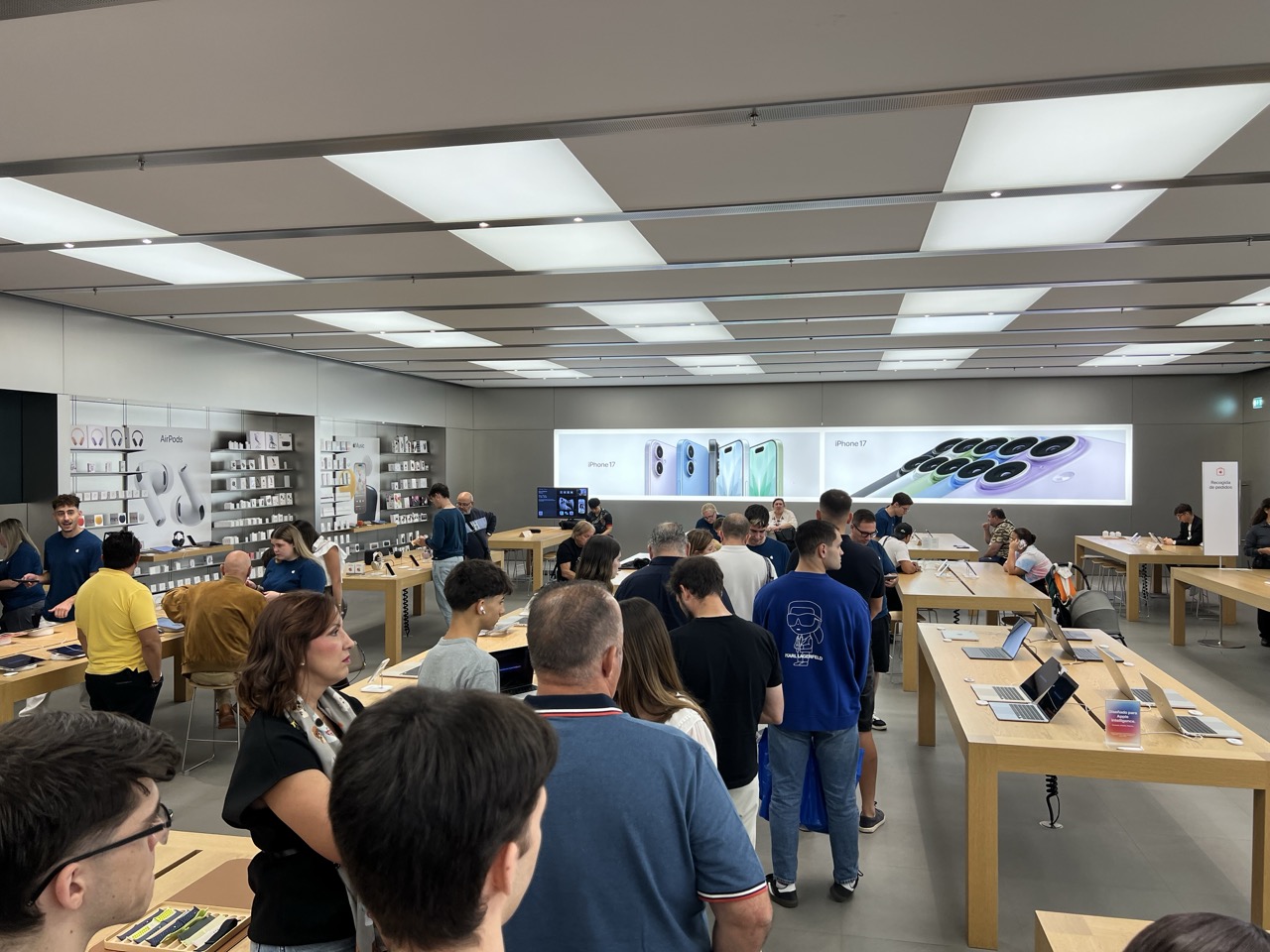La gente haciendo cola en una Apple Store, con carteles del iPhone 17 de fondo